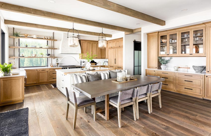 Kitchen with maple cabinets, exposed ceiling beams, wood floors, dining nook, table, chairs, shelves, pendant lights, and window