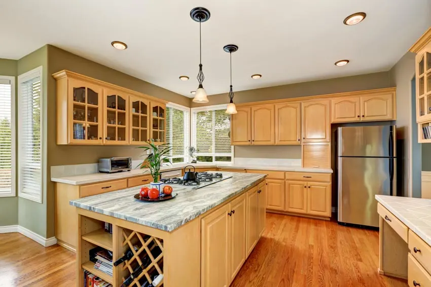Kitchen with light maple cabinets, island, countertops, refrigerator, and windows