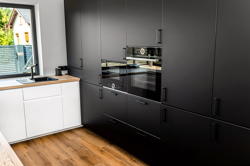 Kitchen with modern cabinet hardware, black cabinets, and wood flooring