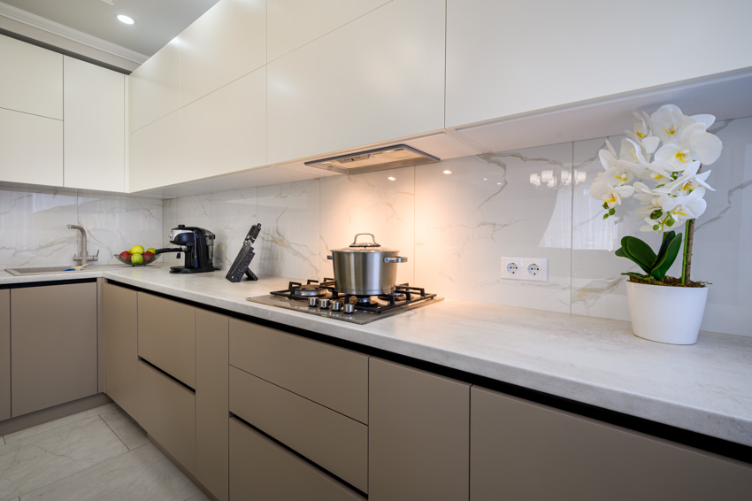 Kitchen with modern cabinets, countertop, stove, and quartzite backsplash