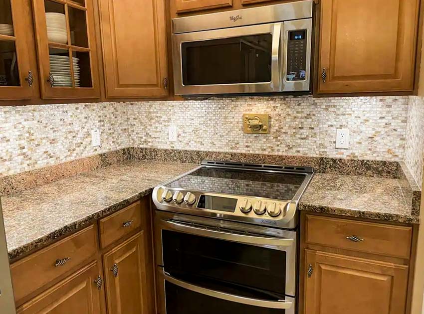 Kitchen with Mother of Pearl backsplash tile, wood cabinets, stove, oven, and countertops