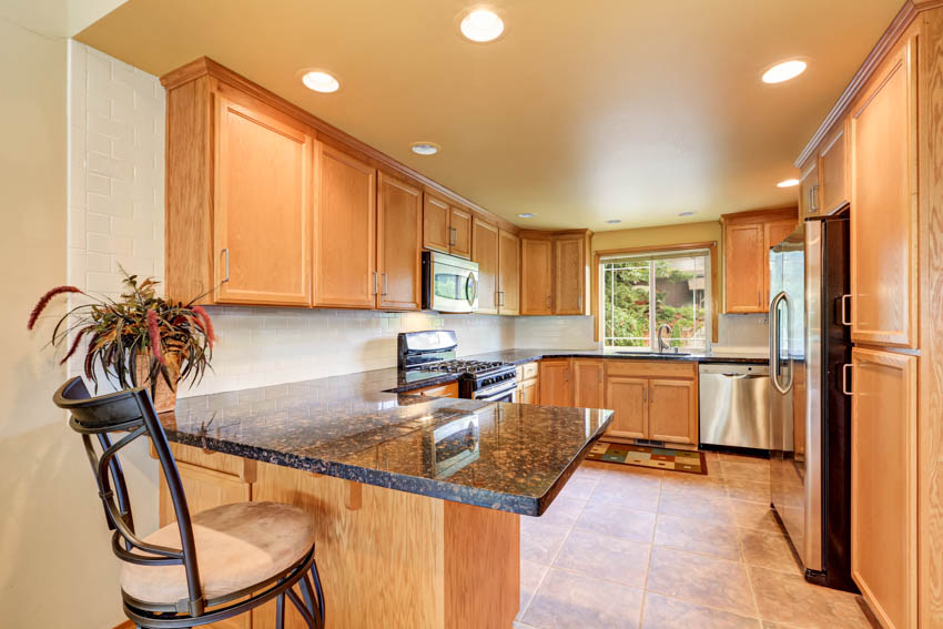 Kitchen with natural maple cabinets, countertops, high chair, window, and ceiling lights