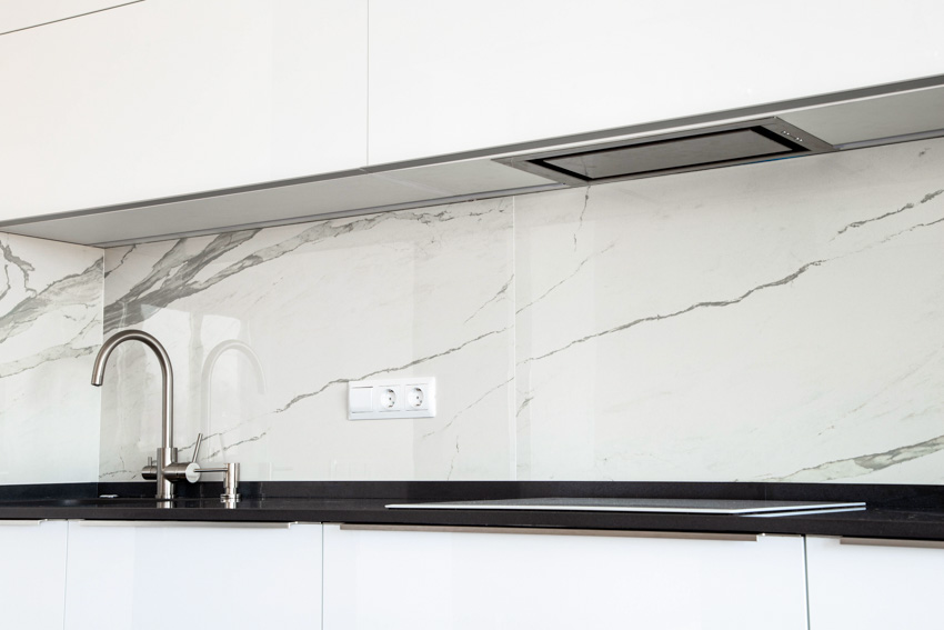 Kitchen with glossy quartzite slab backsplash, faucet, and black countertop