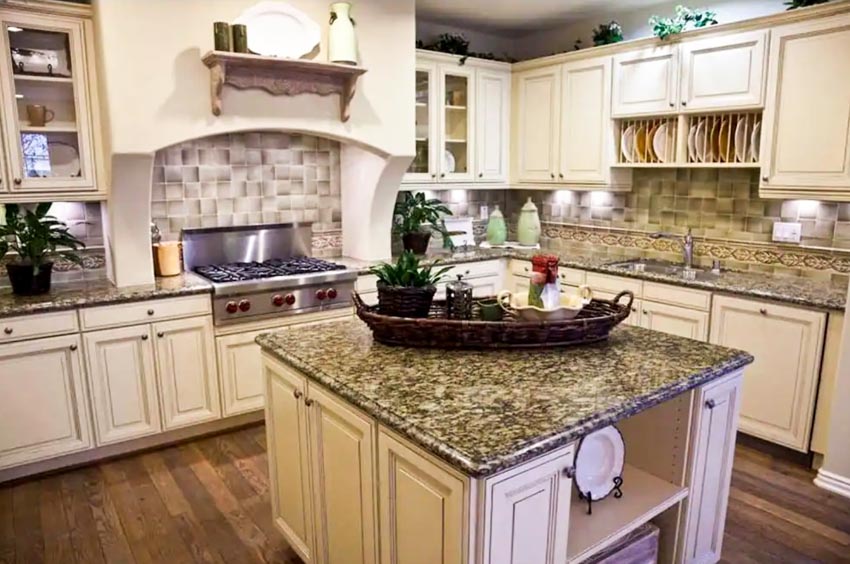 Kitchen with Santa Cecilia granite gold countertop, island, wood flooring, backsplash, stove, and cabinets