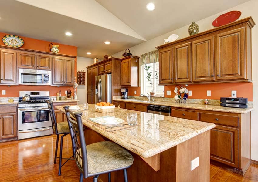 Kitchen with traditional cabinet hardware, countertops, island, chairs, oven, ceiling lights, and window