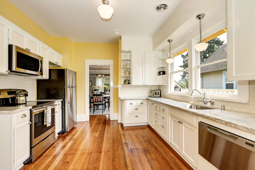 Kitchen with unfinished Tigerwood flooring, white cabinets, countertop, oven, stove, ceiling lights, yellow walls, and windows