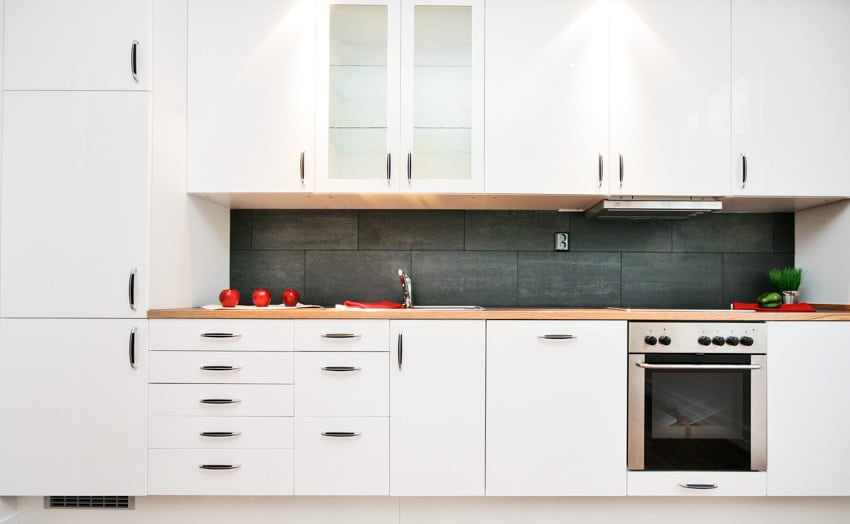 Kitchen with white cabinets, backsplash, countertop, and enameled hardware