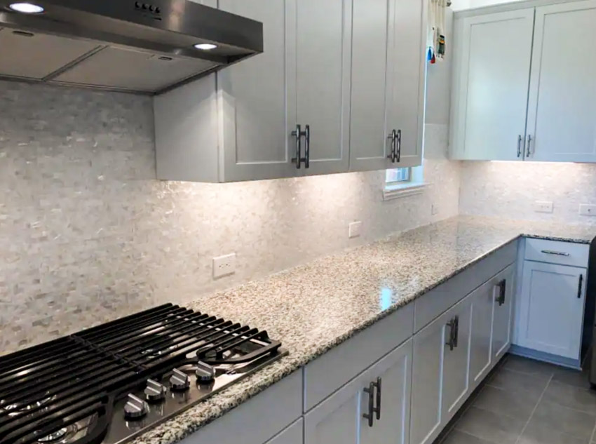 Kitchen with countertop stove, pewter hood and counter