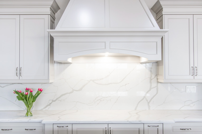 Kitchen with white cabinets, and quartzite backsplash