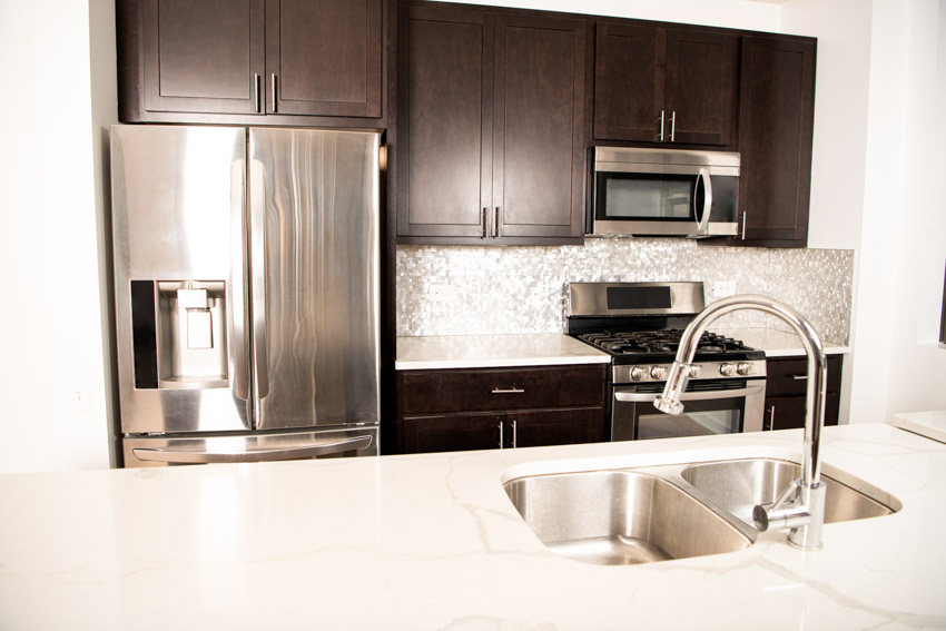 Kitchen with refrigerator in chrome finish and counter with sink and faucet