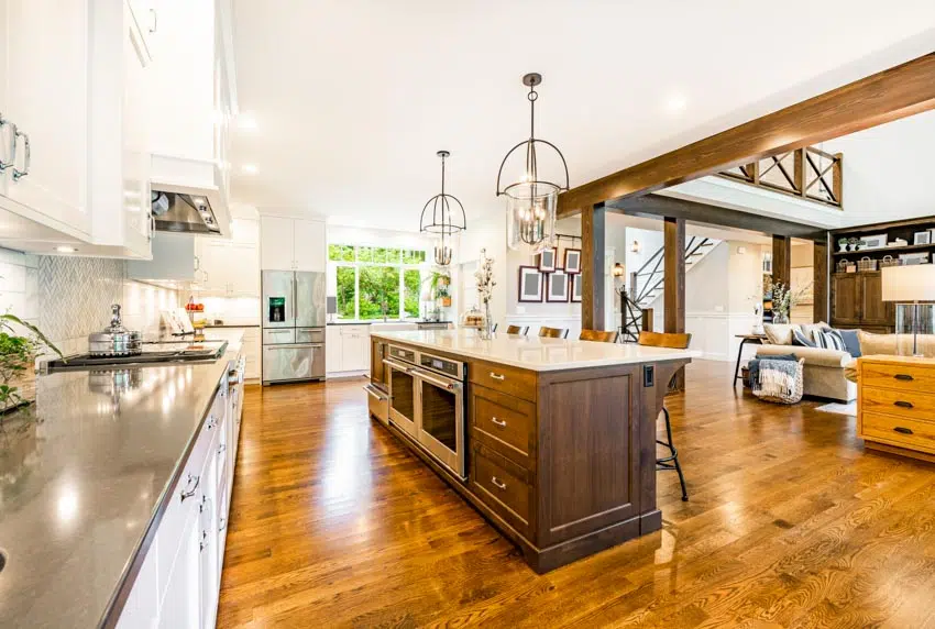 Kitchen with wood flooring, pendant lights, cabinets, windows, and microwave in island