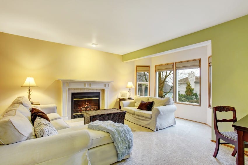 A living room interior with lime green walls, fireplace and white sofas