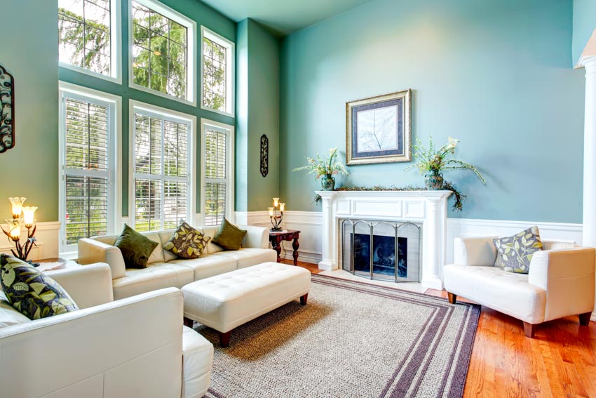 Living room with aqua walls, fireplace, sofa, accent chair, rug, wood flooring, and window