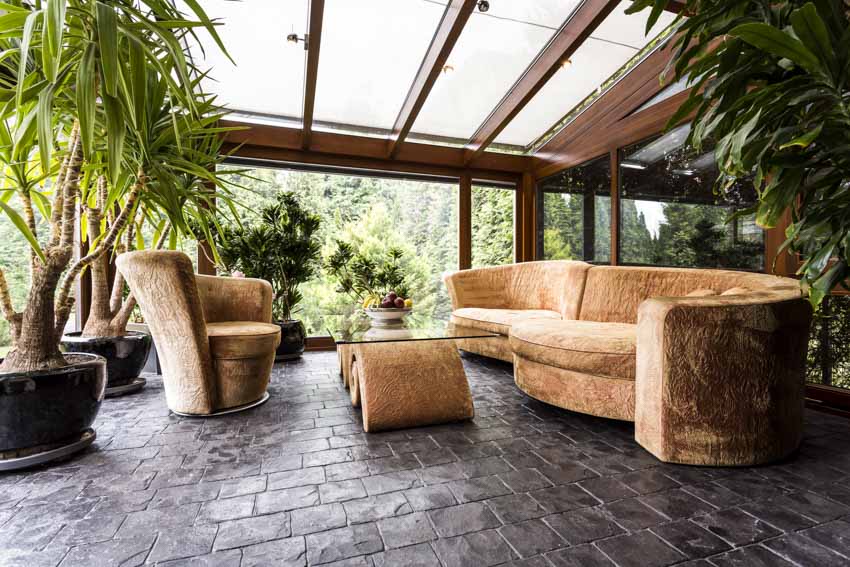 Room with couch, accent chair, coffee table, indoor plants and glass windows