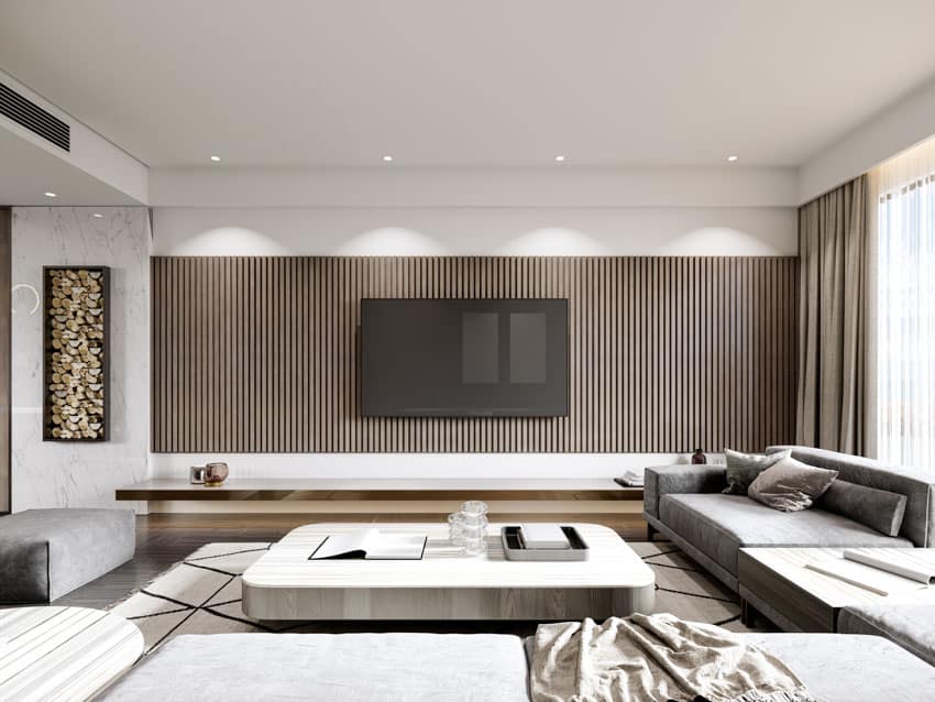 Living room with wood slat TV wall, floating console, sofa, ottoman, ceiling lights, carpet, and windows