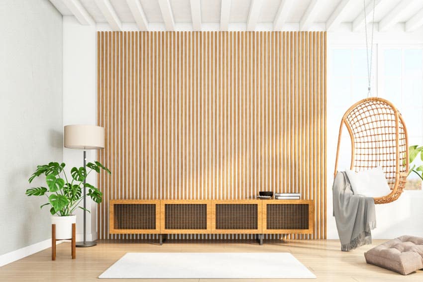 Living room with wood slat accent wall, console table, lamp, egg chair, and ceiling beams