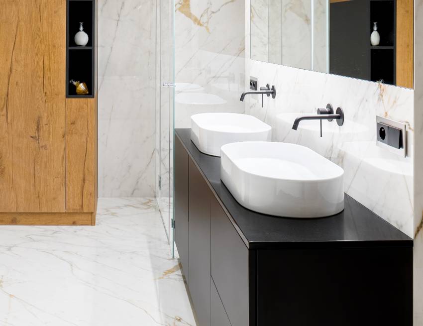 Luxury bathroom with marble tiles on floor and walls, wooden closet, two washbasins and granite countertop