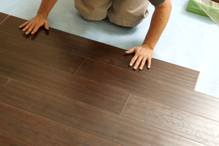 A man installing new laminate wood flooring in a floating method