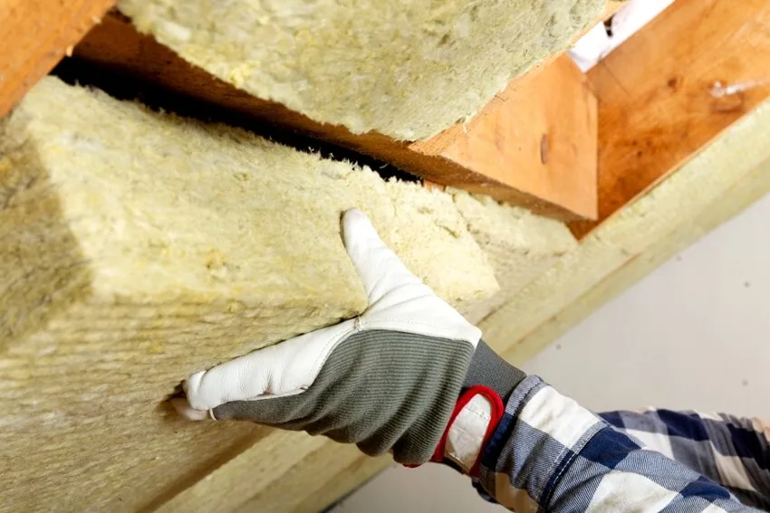 A man installing thermal roof insulation layer using wool panels