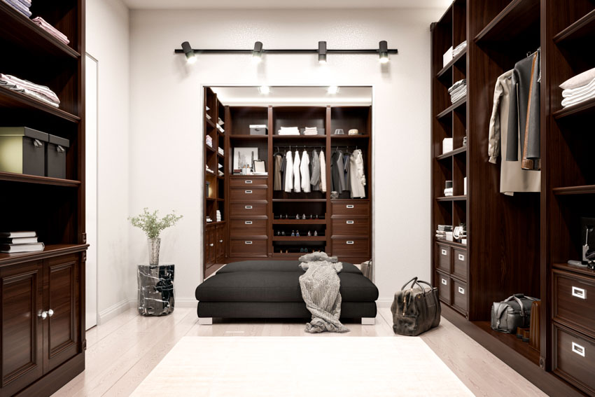 Men's closet with closet organizer, ottoman, indoor plant, and track lighting