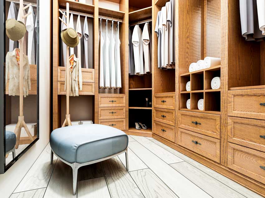 Men's closet with wood plank floors, drawers, shelves, hangers, and mirror