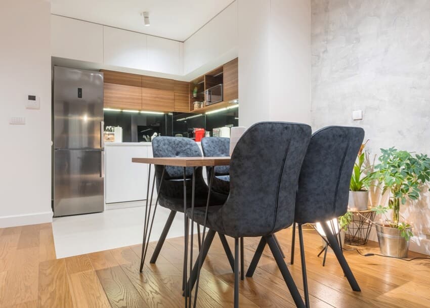 Minimalist modern dining and kitchen area with floating laminate floors, plants and dining set
