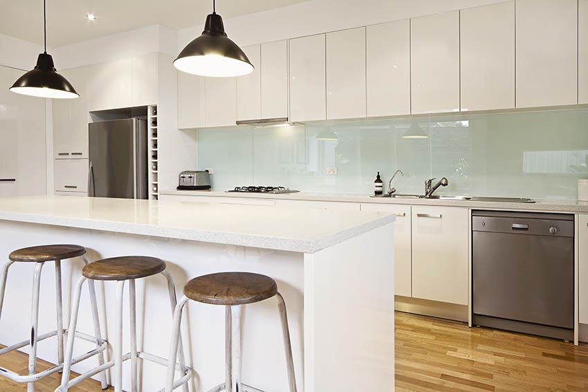 Modern kitchen with white cabinets aqua glass backsplash wood floors