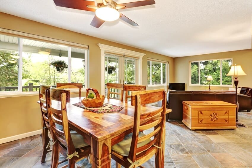 Open plan dining room with rustic wooden table and chair set. connected to the living room with natural stone flooring