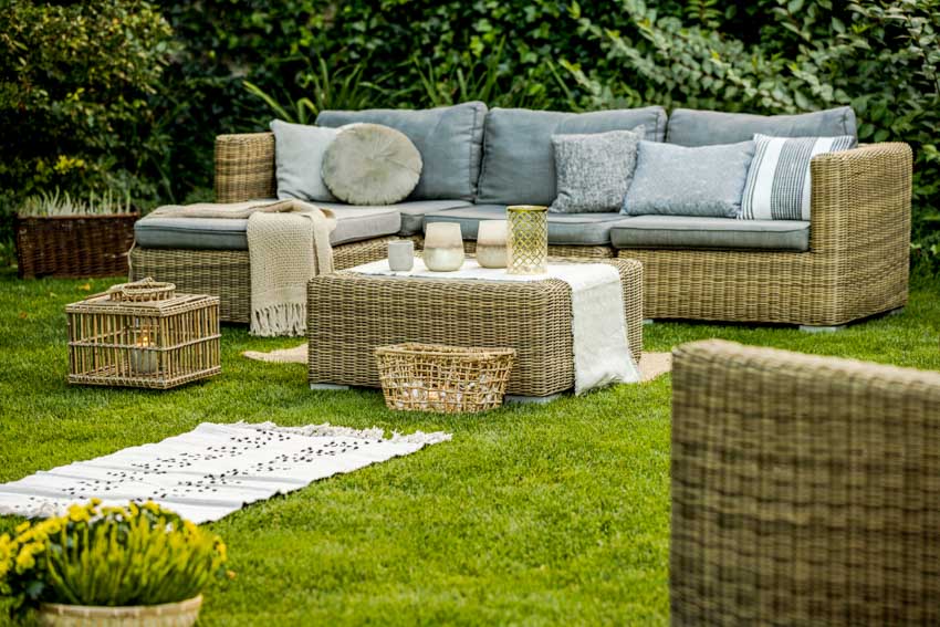 Backyard with plants, table and cushioned couch on grass