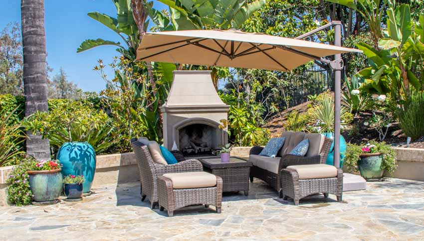 Outdoor patio with fireplace, table, chairs, pavers, and cantilever umbrella