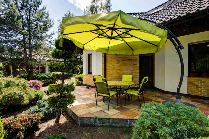 Outdoor patio with offset umbrella, chairs, table, tile deck, and plants