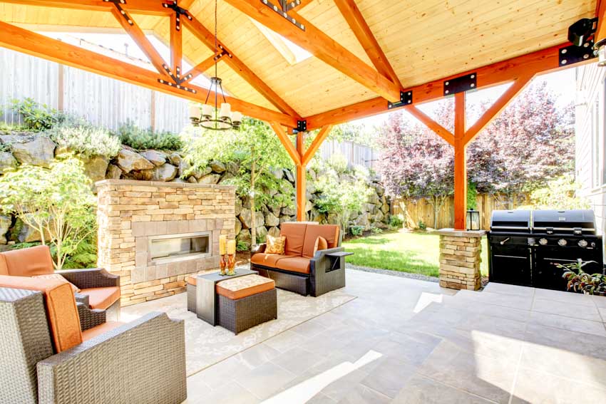 Outdoor patio with quartz pavers, fireplace, cushioned sofa, coffee table, grill, and roof