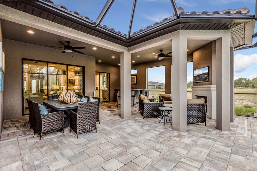 Outdoor paved patio with wet rated ceiling fans, chairs, and tables