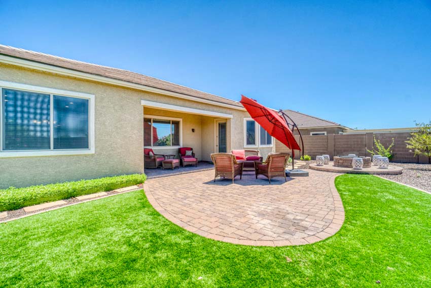 Outdoor paver patio with table, chairs, grass, and cantilever umbrella