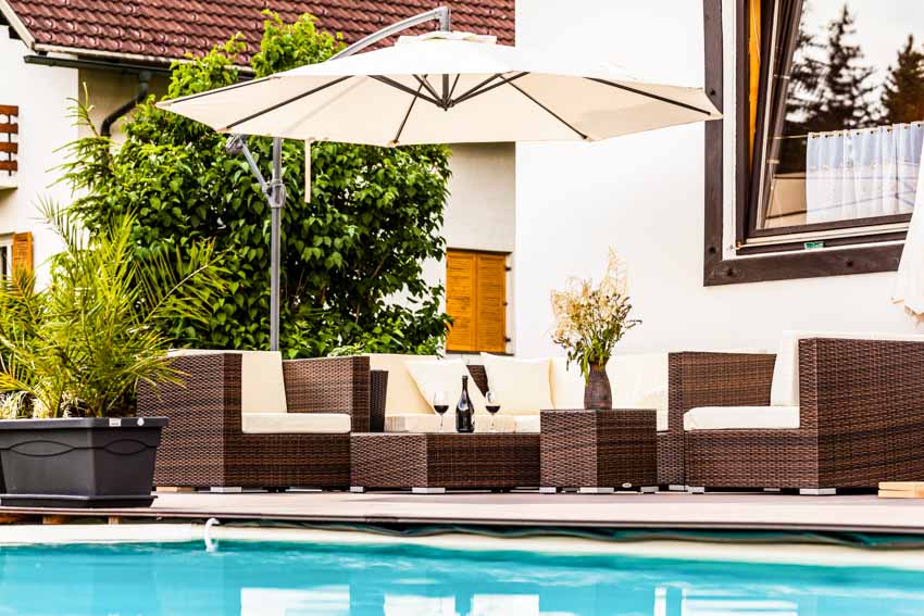Outdoor pool deck with cushioned chairs and offset umbrella