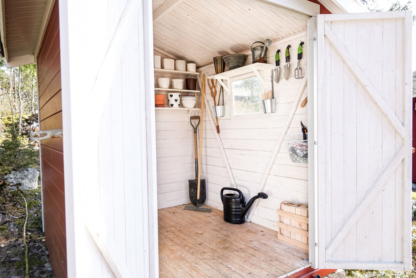 Outdoor shed with wood floor, shelves, and tools