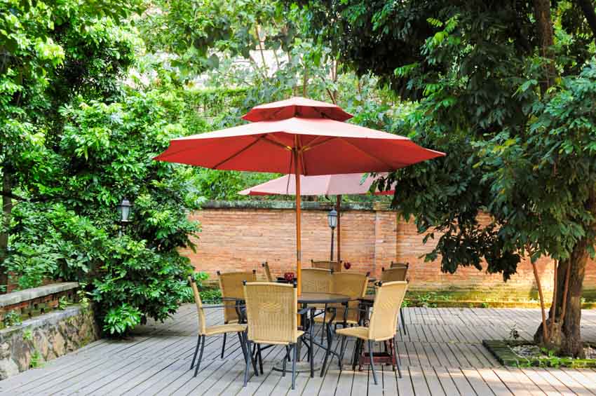 Outdoor wood deck with trees, fence, table, chairs, and cantilever umbrella