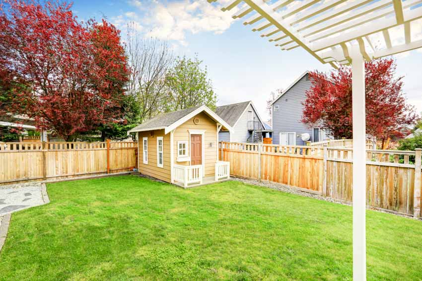 Outdoor yard with pressure treated fence, shed, and grass