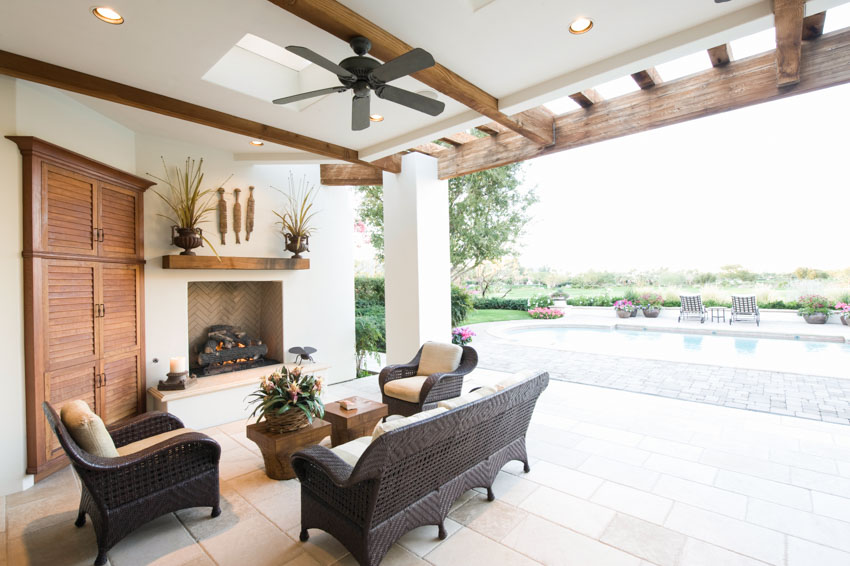 Patio with outdoor ceiling fan, fireplace, sofa chairs, and swimming pool