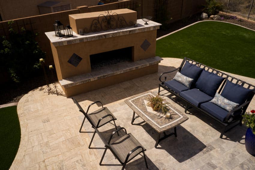 Patio with travertine pavers, outdoor fireplace, chairs, and coffee table