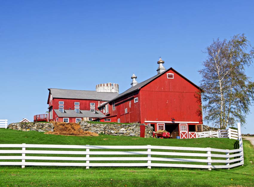 Red barn with pitched roof, ventilation, and split rail fences