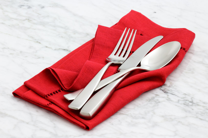 Silver knife fork and spoon on top of red napkin