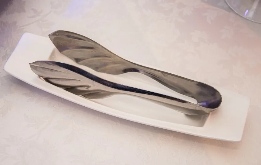 Silver tongs on top of a rectangular plate
