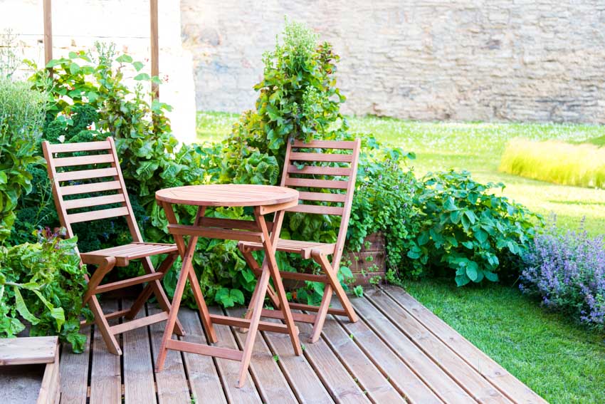 Small deck with wood table and chairs on grass with plants