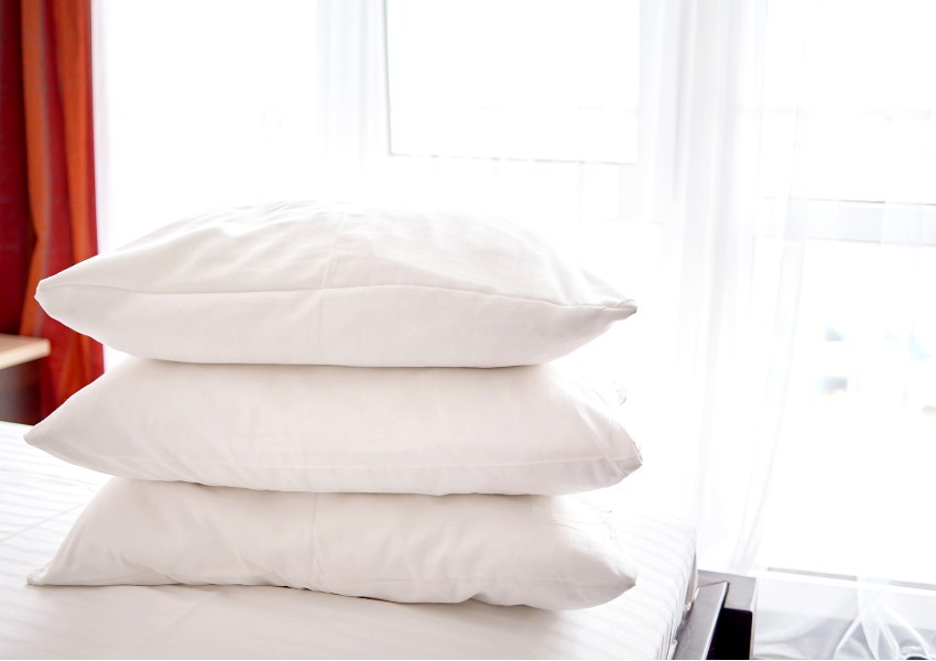Stack of white soft pillows on comfortable bed sheet 
