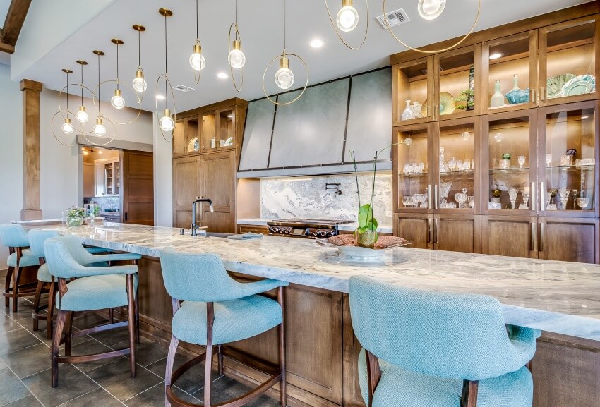 Stunning kitchen interior with long island and ultra compact countertop, wooden accents, chairs, and pendant lights