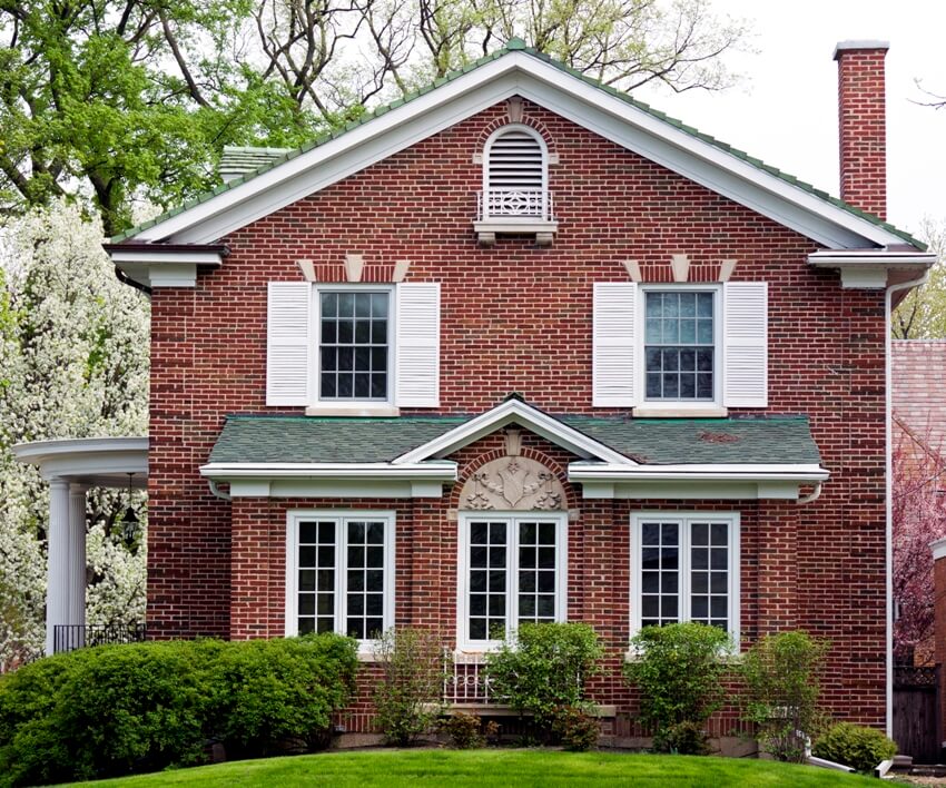 Traditional American red brick home with white shutters on windows