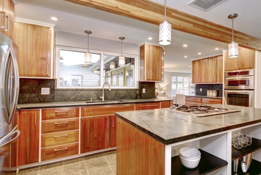 Traditional kitchen room with dark gray counter tops, wooden teak cabinets and stainless steel appliances