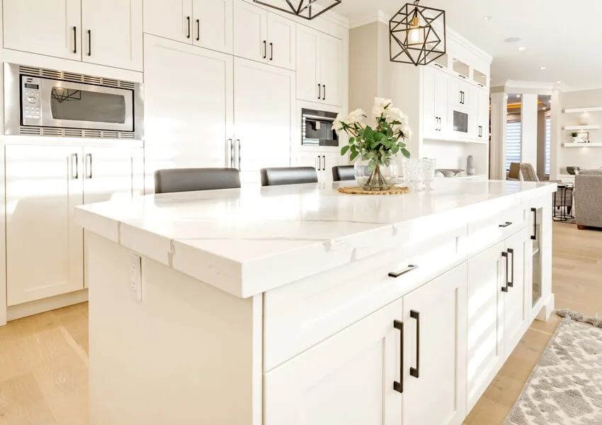 White kitchen interior with island that has contact paper countertop and white cabinets