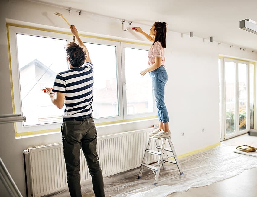 Couple painting room with paint brush and step ladder